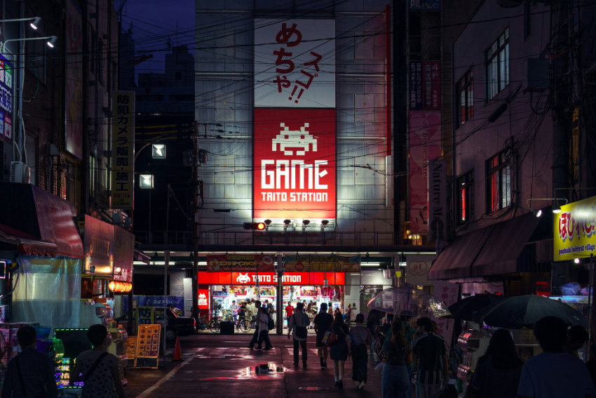 TAITO Station Arcade Center in Osaka bei Nacht mit leuchtendem Game-Schild und Besuchern auf der Straße