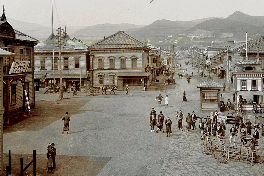 Straßenszene in Otaru auf Hokkaidō im Jahr 1909 Historische Straßenszene aus Otaru auf Hokkaidō im Jahr 1909, mit Geschäften, Passanten und frühen modernen Gebäuden der Meiji-Zeit