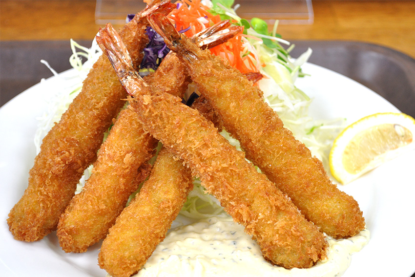 Goldbraun frittierte Ebi-Tempura-Garnelen mit Zitronenspalte und Beilage – beliebtes japanisches Tempura-Gericht