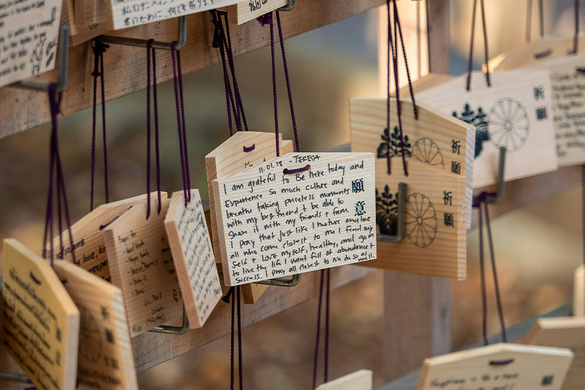 Beschriftete Ema Holztafeln mit violetten Kordeln an einem Ema-Gestell im japanischen Schrein