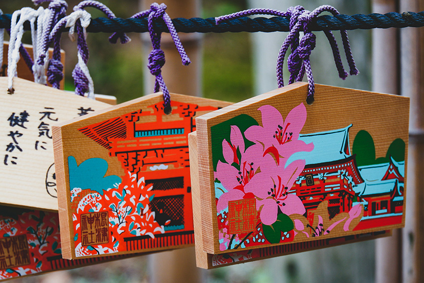 Bunte Ema Holztafeln (japanische Wunschtafeln) mit violet-ten Schnüren am Nezu Shrine in Tokio aufgehängt