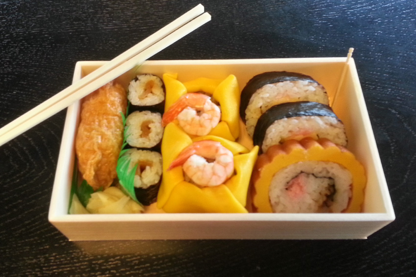 Japanische Bento-Box mit Sushi, Inari-Sushi, Maki und Garnelen – typisches japanisches Alltagsessen