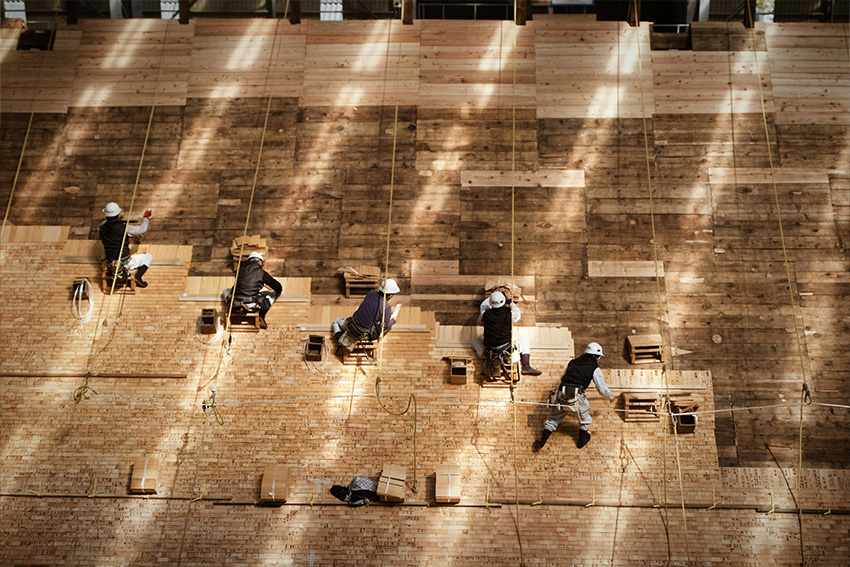 Japanische Handwerker bei der präzisen Arbeit auf einer Holzfläche – Sinnbild für Disziplin, Teamarbeit und Perfektion im japanischen Arbeitsstil