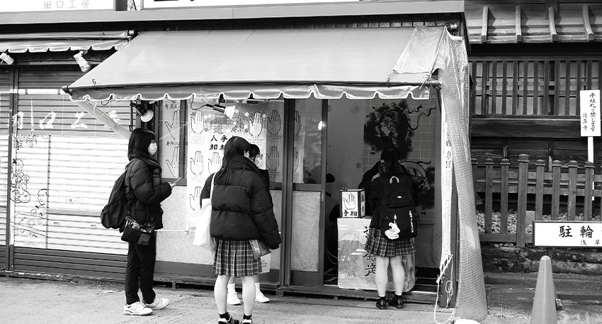 Tesō Uranai – Handlesen in Japan auf einem Markt in Tokio Japanischer Tesō Uranai Stand in Asakusa, Tokio – Handleser bietet Deutung der Handlinien an