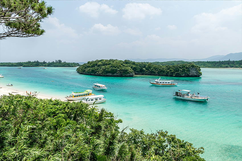Türkisblaues Wasser, kleine Boote und grüne Inseln in Okinawa im Sommer