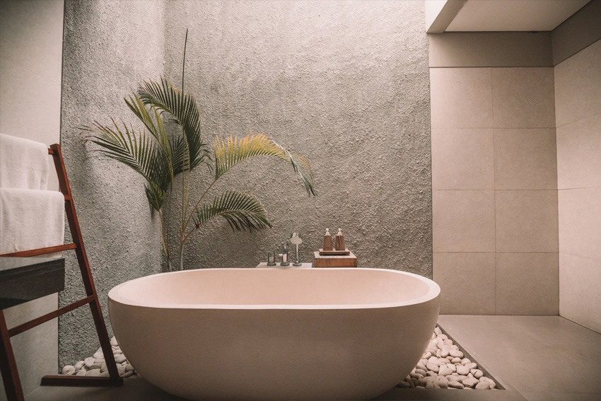 Japandi Badezimmer mit freistehender Badewanne, Naturtönen, Steinwand und reduzierter Gestaltung