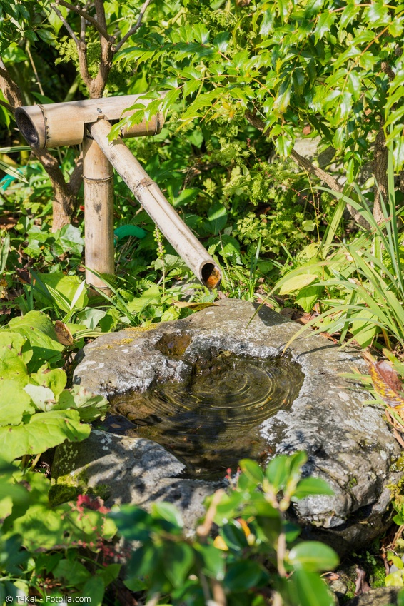 Wasserspeier aus Bambus mit Steinbecken im Grünen