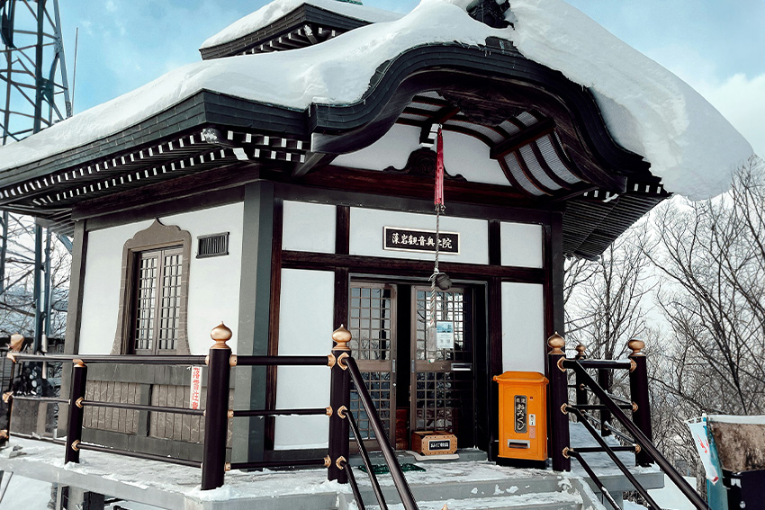 Moiwa Kannon Okunoin auf dem Mt. Moiwa in Sapporo mit verschnei-tem Dach, Treppe und buddhistischer Architektur im Winter
