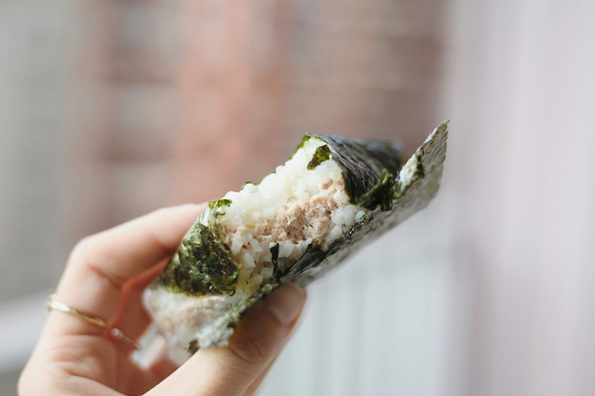 Onigiri mit Reis und Füllung, in Nori gewickelt und in der Hand gehalten – beliebtes japanisches Alltagsgericht