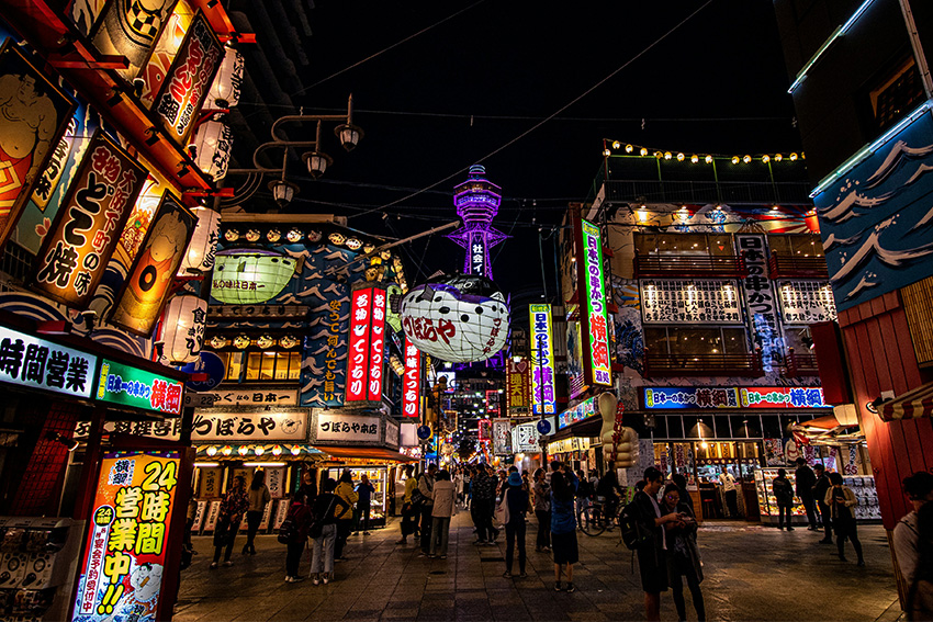 Shinsekai bei Nacht mit Tsūtenkaku-Turm in Osaka Belebtes Nachtleben im Viertel Shinsekai in Osaka mit Neonlichtern, Restaurants und dem Tsūtenkaku-Turm im Hintergrund