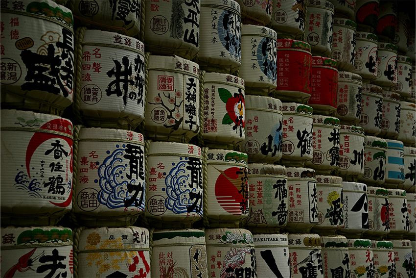 Gestapelte traditionelle Sake-Fässer mit japanischer Kalligrafie als Sinnbild für die Geschichte und Herstellung von Sake in Japan
