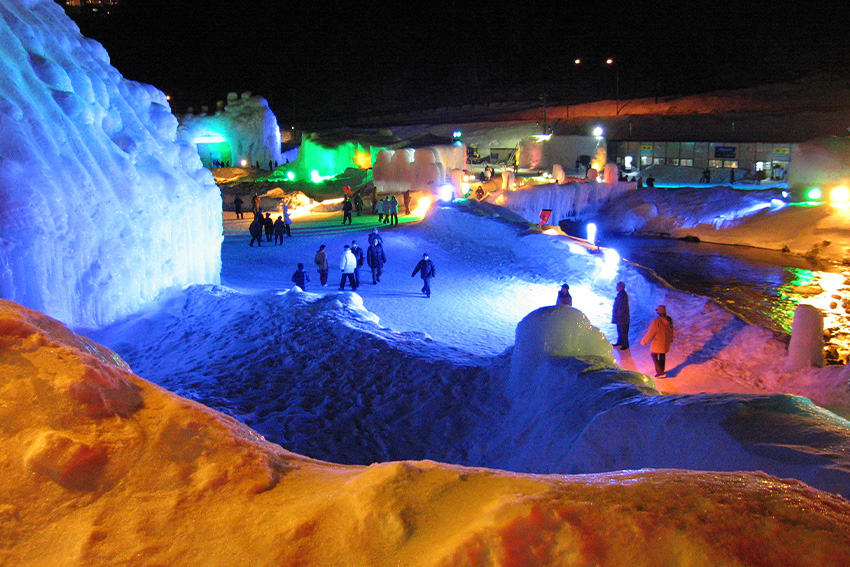 Begehbare Eisskulpturen und farbige Illuminationen beim Sōunkyō-Onsen Eiswasserfall-Festival auf Hokkaidō bei Nacht