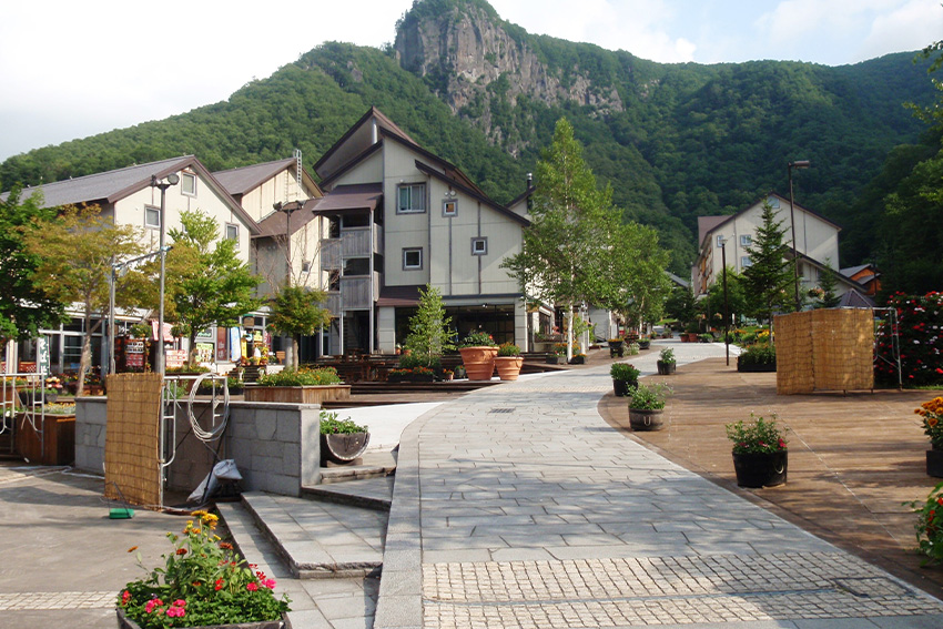 Promenade im Onsen-Ort Sōunkyō mit Hotels und Bergkulisse im Daisetsuzan-Nationalpark auf Hokkaidō