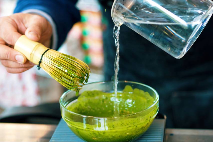 Matcha-Zubereitung als Teil japanischer Achtsamkeit und Wellness Zubereitung von Matcha mit Bambusbesen und heißem Wasser als meditativer Moment in der japanischen Tee- und Wellnesskultur