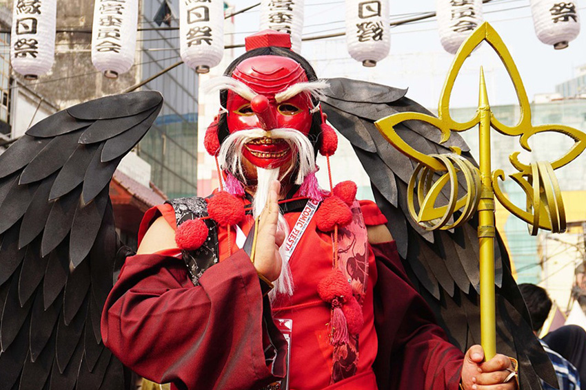 Tengu-Darsteller mit Flügeln und Maske bei einem japanischen Straßenfest