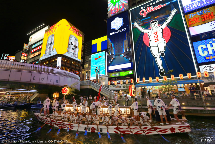 Boot mit Festival-Teilnehmern vor Glico Man in Osaka