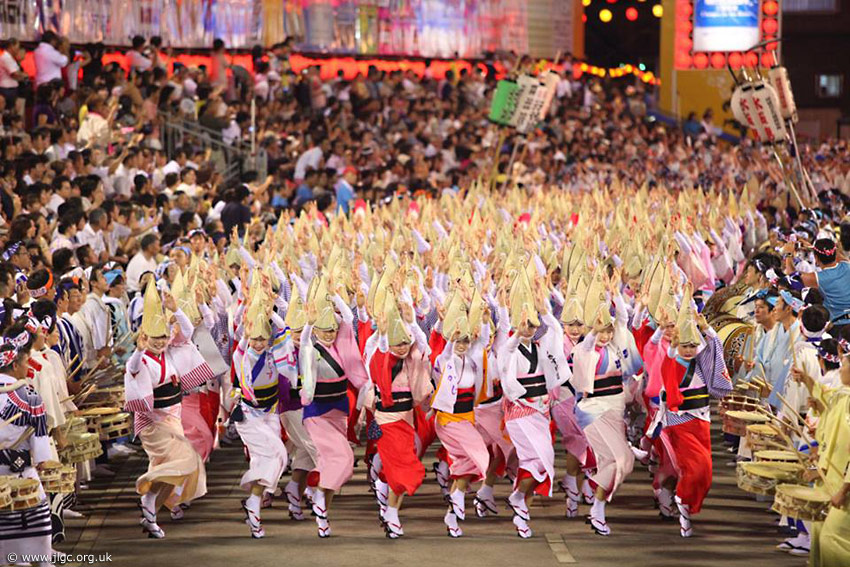 Tanzende Frauen mit typischen Hüten für den Awa Tanz in einer Parade