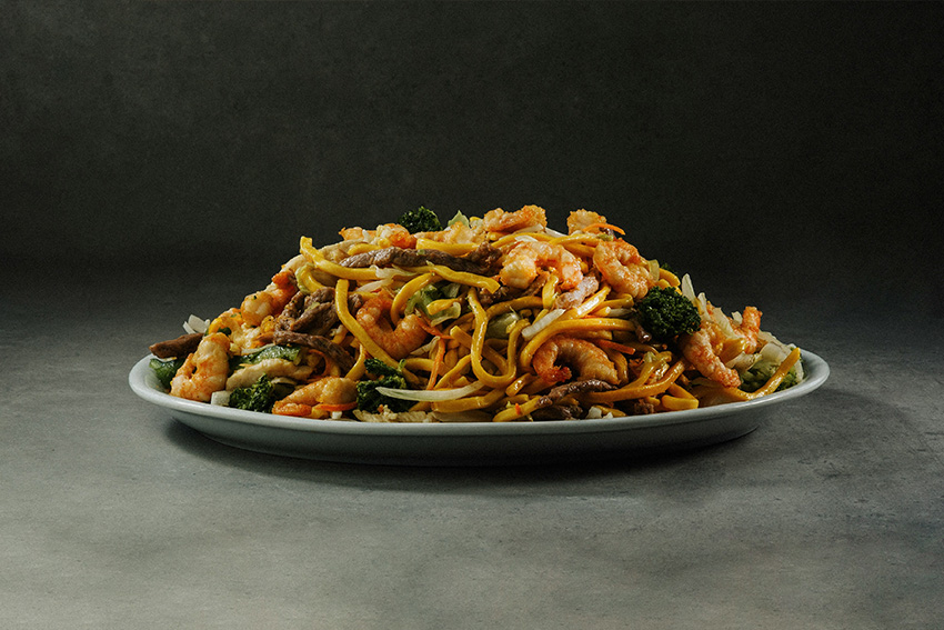 Schnelles Yakisoba Gericht mit Nudeln, Gemüse, Garnelen und Fleisch auf einem Teller serviert